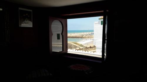 a window with a view of a beach and the ocean at The Jewel of the Northern Moroccan Atlantic in Asilah in Asilah