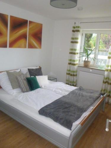 sypialnia z łóżkiem z białą pościelą i poduszkami w obiekcie Apartment Maximilian w mieście Kösching