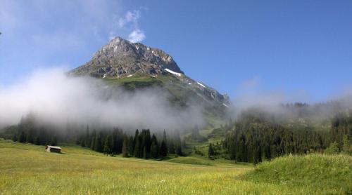 a mountain in the middle of a field with clouds at Appartement Omeshorn anno 1593 in Lech am Arlberg