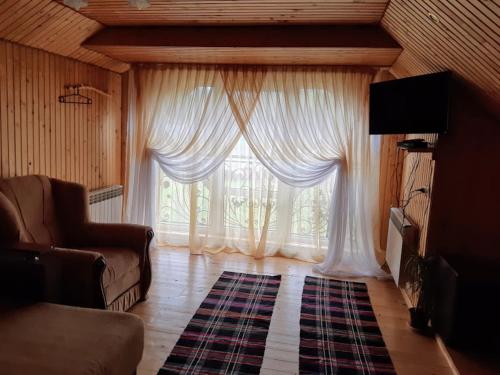 a living room with a large window with white curtains at Gostynna Rodyna in Izki