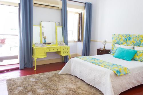 a bedroom with a bed and a yellow table with a mirror at Casa dos Tios Estremoz-veiros in Veiros