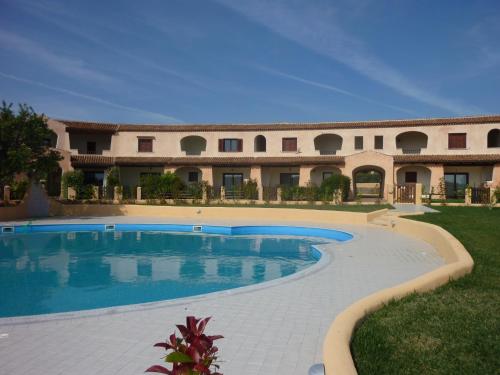 een groot gebouw met een zwembad ervoor bij Residence Le Ginestre / Ataras in Porto San Paolo