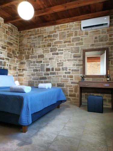 a stone walled bedroom with a bed and a piano at Angela in Triopetra