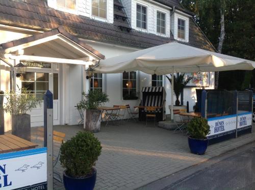 a patio with an umbrella in front of a house at Dünenhotel am Meer in Warnemünde