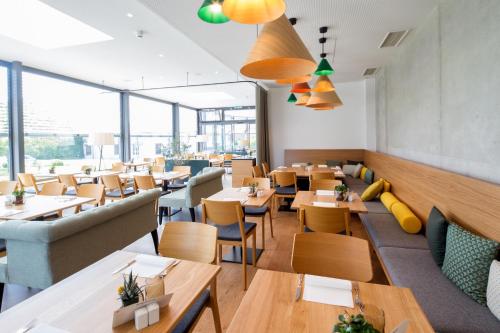 um restaurante com mesas, cadeiras e janelas em Adler Hotel & Gasthaus em Nonnenhorn