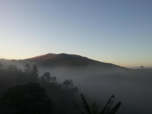 a misty mountain with a hill in the background at Ecole Lodge Antananarivo in Mahitsy
