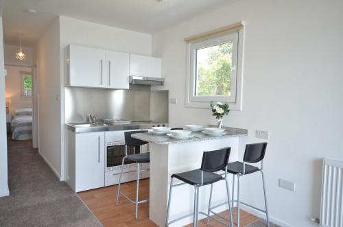 a kitchen with white cabinets and a counter with stools at Premium Lake Lodges in Chichester
