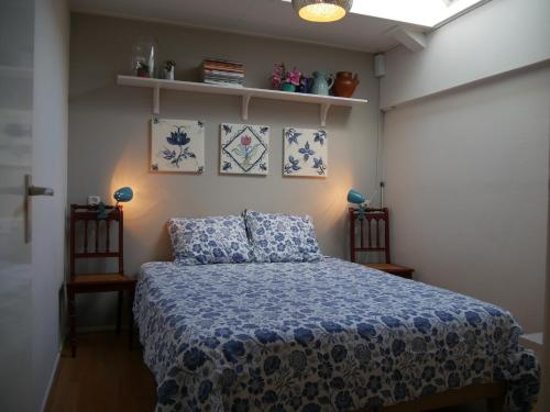 Schlafzimmer mit einem Bett mit einer blauen und weißen Bettdecke in der Unterkunft d'AldeSkoalle in Molkwerum