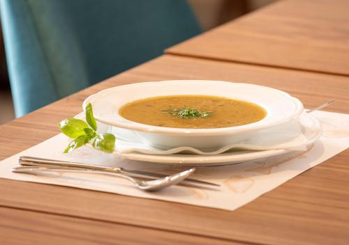 a bowl of soup on a plate on a table at Hotel Nais in Niš