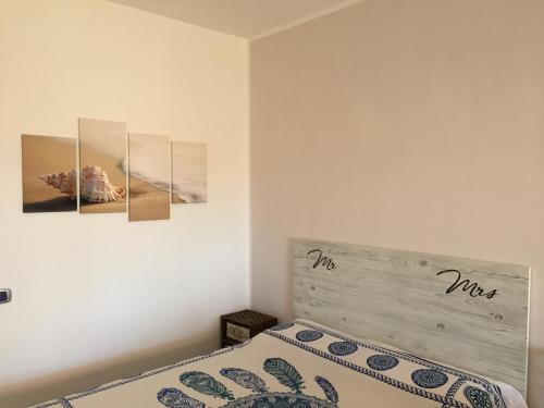 a bedroom with a bed with three paintings on the wall at Portorosa Vista Mare in Furnari