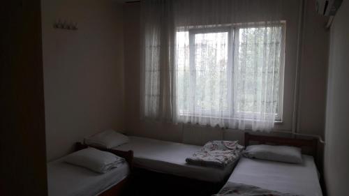 two beds in a room with a window at FİLİZ PANSİYON in Denizli