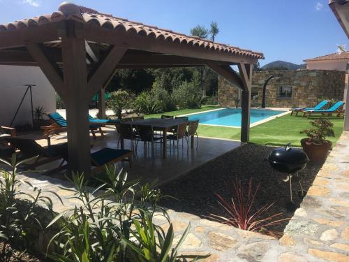 un patio avec une table et des chaises et une piscine dans l'établissement Domaine Vermentinu, à Patrimonio