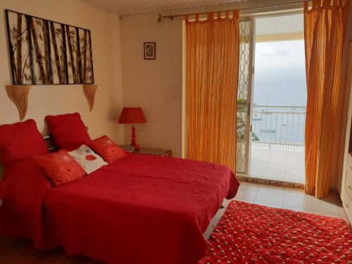 a bedroom with a red bed and a large window at Agréable Studio vue mer au Trois Îlets in Les Trois-Îlets