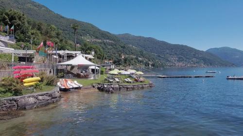 a lake with tables and umbrellas in the water at Residence Casa e Vela in Oggebbio