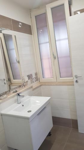 un bagno bianco con lavandino e due finestre di Casa Il Germoglio a Montecatini Terme