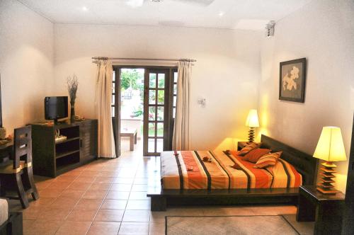 una camera con letto, televisore e porta di Britannia Hotel a Grand'Anse Praslin