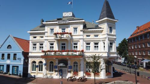 a white building with a clock on top of it at Hotel Hohenzollernhof in Cuxhaven