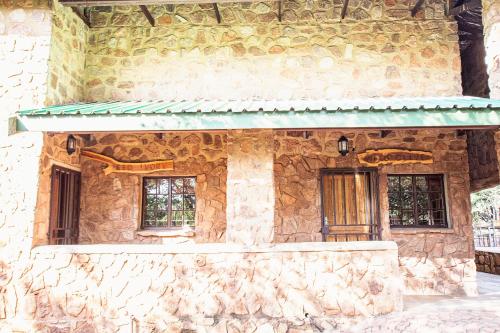 a stone building with a green awning and windows at Milorho Lodge in Rietfontein