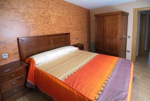 a bedroom with a bed and a wooden dresser at Apartahotel La Corrala in San Martín de Moncayo