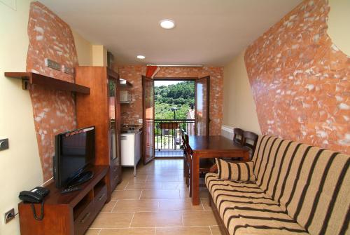 a living room with a couch and a television at Apartahotel La Corrala in San Martín de Moncayo
