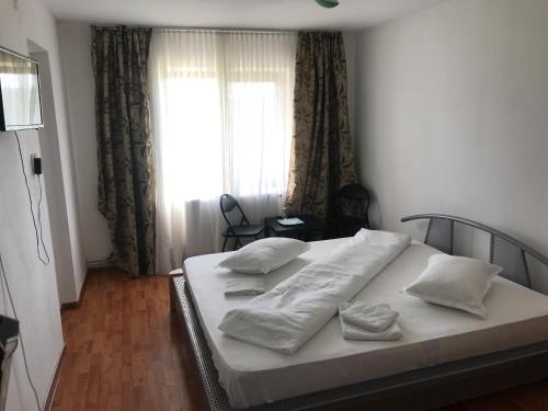 ein Schlafzimmer mit einem Bett mit weißen Laken und einem Fenster in der Unterkunft Casa de vacanta Madalina in Novaci-Străini
