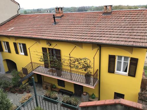 ein gelbes Haus mit einem Balkon und einem Dach in der Unterkunft Noi Due Guest House - Fubine Monferrato in Fubine