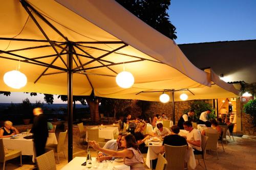 a group of people sitting at tables under an umbrella at Kallikoros Country Resort & Spa in Noto