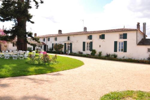 een groot wit huis met een patio en een tuin bij le Logis du Plessis in Chaniers