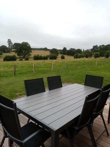 a wooden table with four chairs and a field at La Roulotte Julyana in Vielsalm