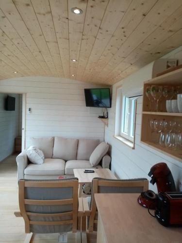 a living room with a couch in a tiny house at La Roulotte Julyana in Vielsalm