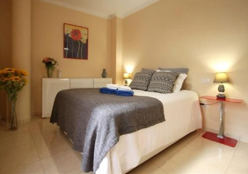 ラスパルマス・デ・グランカナリアにあるMarLenghi Apartmentのベッドルーム1室(ベッド1台、ランプ2つ、花付)