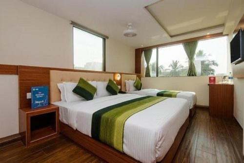 a bedroom with a large white bed with green pillows at Aflon Hotel in Mumbai