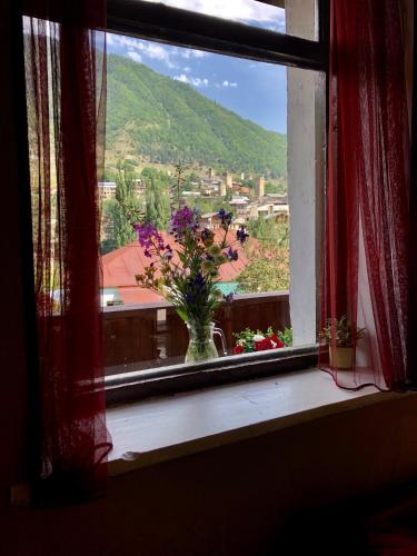 a vase of flowers sitting on a window sill at Travel Inn House Mestia • მოგზაურის სახლი in Mestia