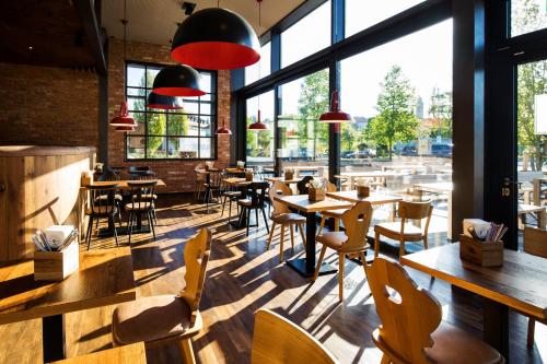 a restaurant with tables and chairs and large windows at RiKu HOTEL Pfullendorf in Pfullendorf