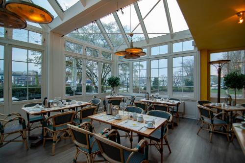 un restaurante con mesas y sillas en una habitación con ventanas en Hotel & Restaurant Alter Speicher en Greifswald