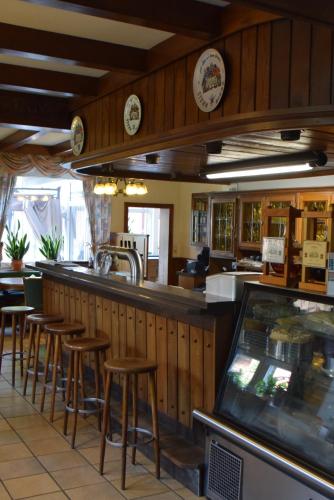 a restaurant with a bar with stools at a counter at Gasthof Waldesruh in Saerbeck