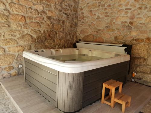Cette chambre dispose d'une baignoire et d'un mur en pierre. dans l'établissement Casa dos Namorados, à Vale de Cambra