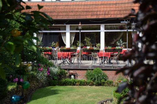 a patio with tables and chairs in a garden at Gasthof Waldesruh in Saerbeck