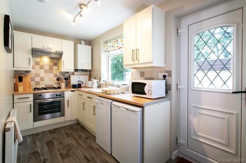 a white kitchen with white cabinets and a microwave at AIRE VUE - Skipton in Skipton