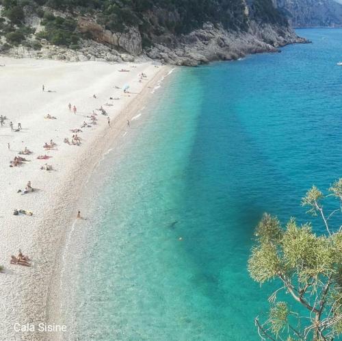 a beach with a group of people in the water at Sa Dommu 'e su coro in Triei