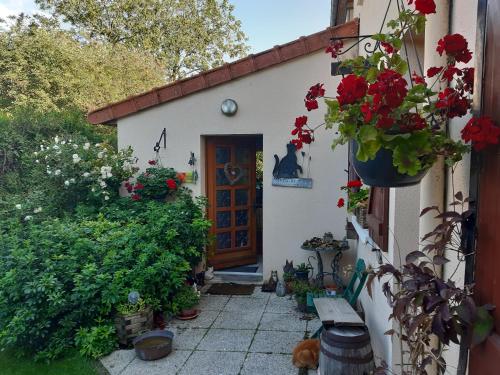 Una pequeña casa con una puerta con flores. en Les Alouettes B&B en Hardecourt-aux-Bois