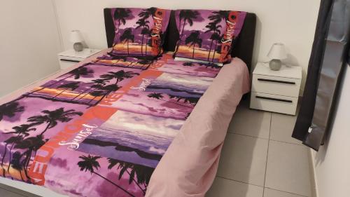 a bed with a purple bedspread with palm trees on it at LE SHANTI in Saint-Pierre