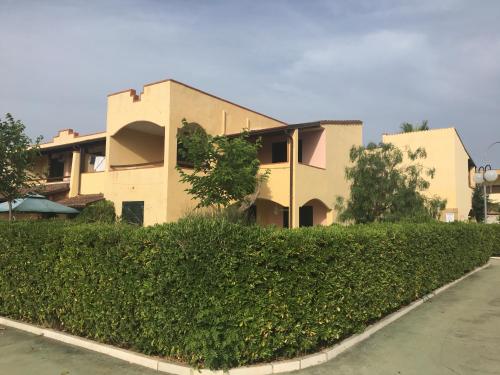 a building with a hedge in front of a house at Villa Marina di Pisticci - Matera in Marina di Pisticci