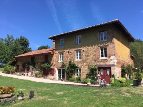 a large brick house with a red door in a yard at Le moulin de Varax in Saint-Paul-de-Varax