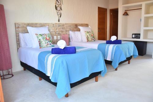 two beds in a room with blue and white sheets at Soho Boutique Holbox - Adults Only in Holbox Island