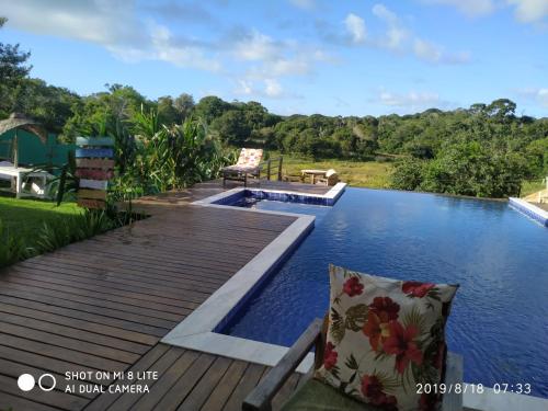 una piscina con terraza de madera junto al agua en Villa Nobre Diniglei, en Trancoso