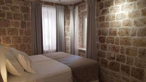a bedroom with a bed in a brick wall at Apartments Milion in Korčula