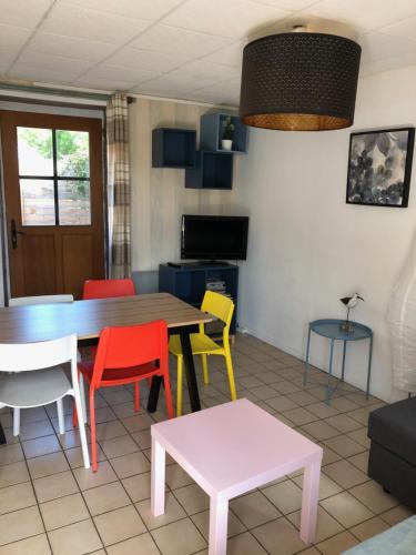 a dining room with a table and colorful chairs at GITE BORD DE MER in Bernières-sur-Mer