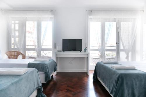 a white room with two beds and a television at 4U Lisbon Suites & Guesthouse VII Airport in Lisbon