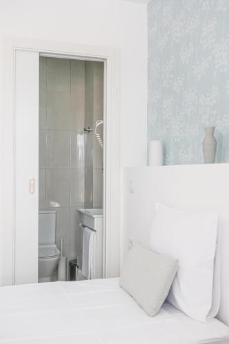 a white bedroom with a white bed and a bathroom at 4U Lisbon Suites & Guesthouse VII Airport in Lisbon